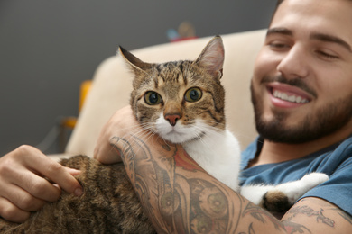 Photo of Happy man with cat on sofa at home. Friendly pet