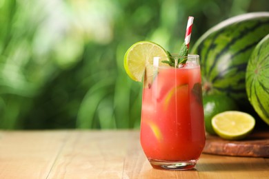 Photo of Glass of freshly made watermelon juice with lime and mint on wooden table outdoors, space for text