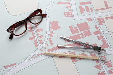 Photo of Office stationery and eyeglasses on cadastral map of territory with buildings