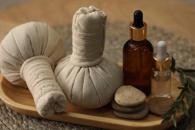Photo of Spa composition. Herbal sacks, cosmetic products and stones on table, closeup