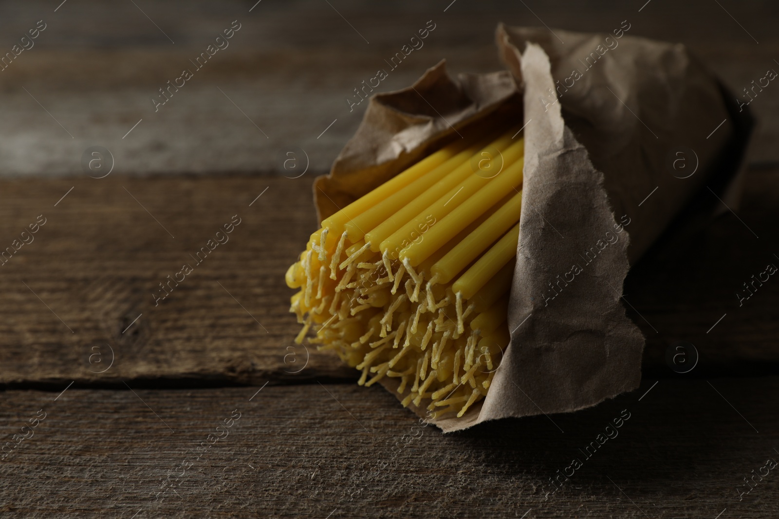 Photo of Many church wax candles on wooden table, closeup. Space for text