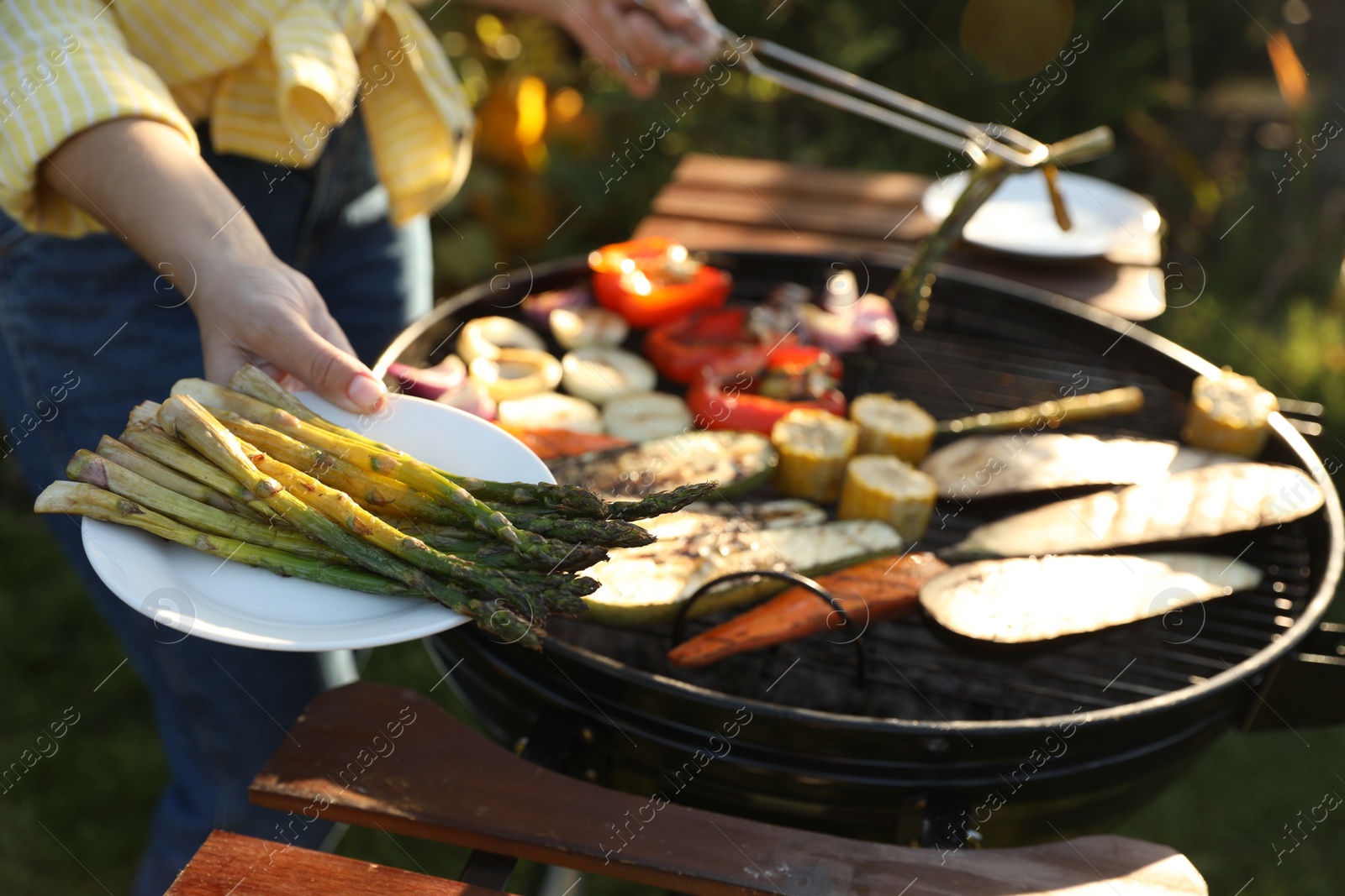 Photo of Woman cooking vegetables on barbecue grill outdoors, closeup