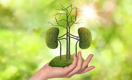 Closeup view of woman with tree in shape of human kidneys against blurred background. Health care concept