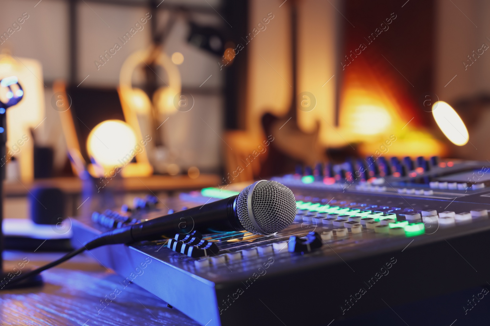 Photo of Microphone and professional mixing console on table in radio studio