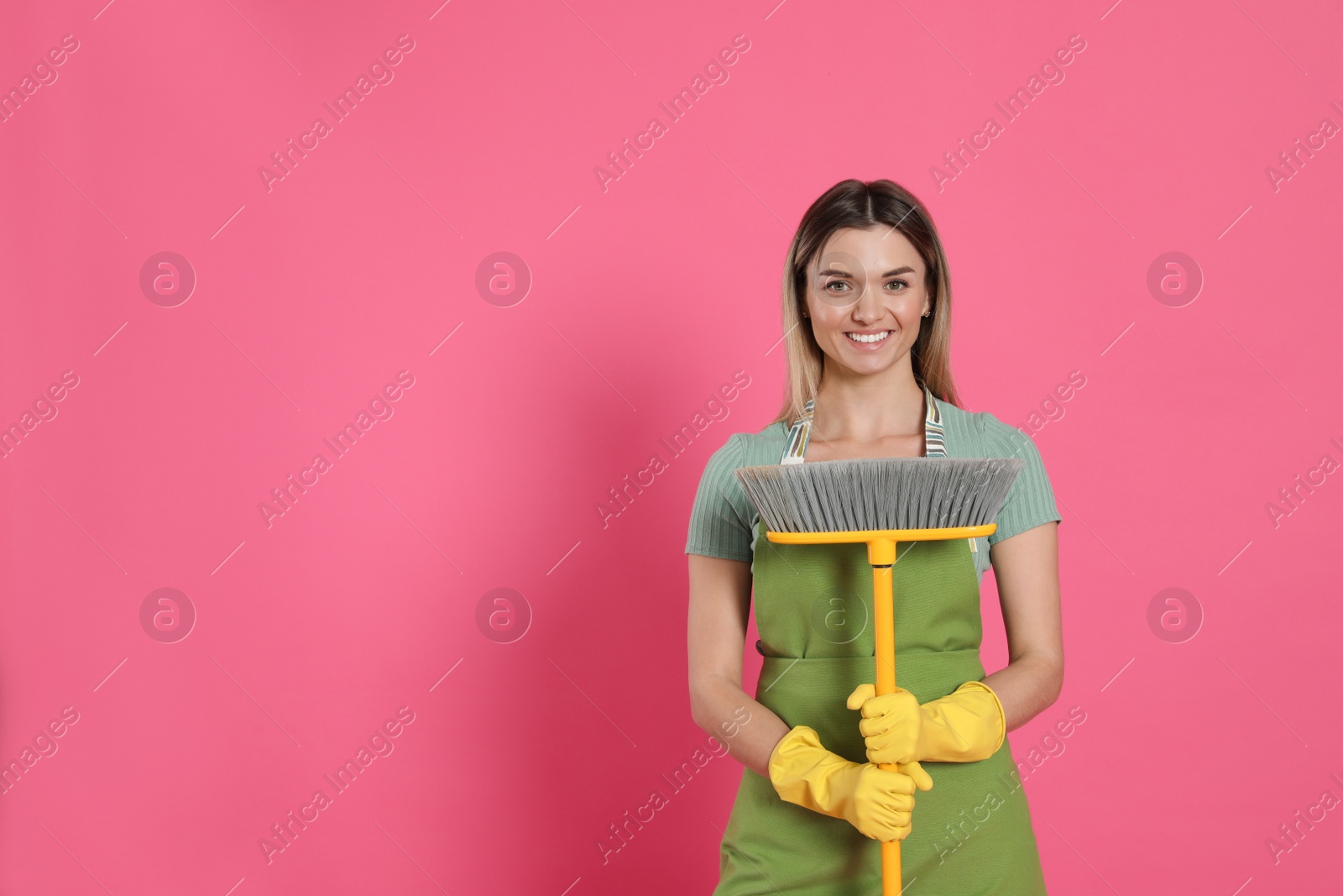 Photo of Young woman with yellow broom on pink background, space for text