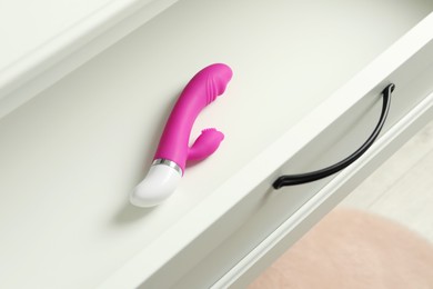 Photo of Modern vibrator in open white drawer. Sex toys