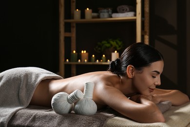 Photo of Young woman receiving herbal bag massage in spa salon