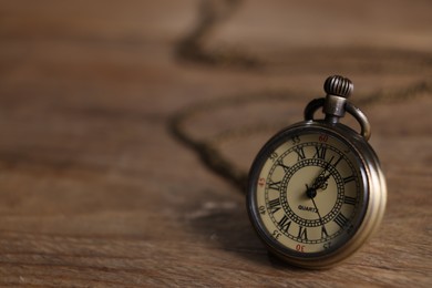 Photo of Pocket clock on wooden table, closeup. Space for text