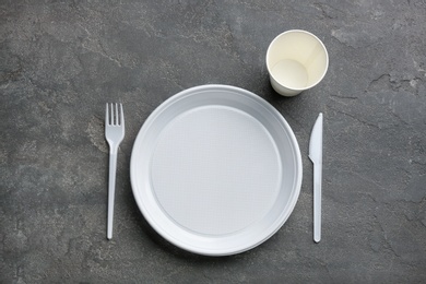 Composition with plastic dishware on grey background, flat lay. Picnic table setting