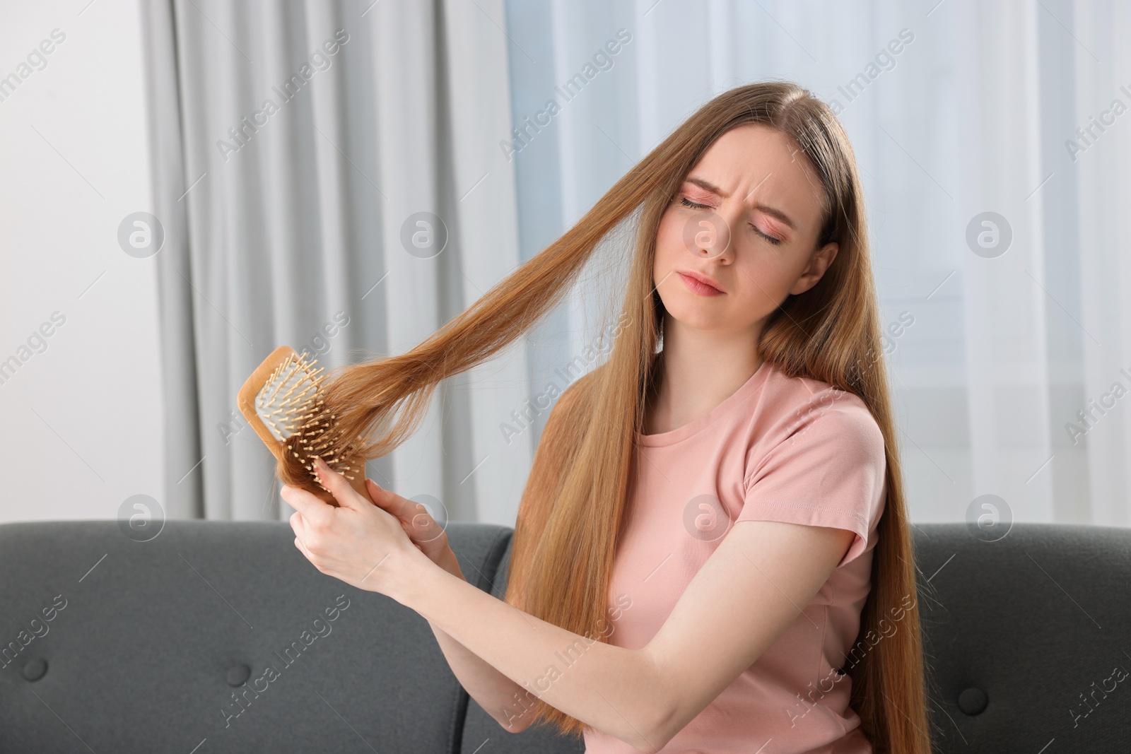 Photo of Upset woman brushing her hair at home. Alopecia problem