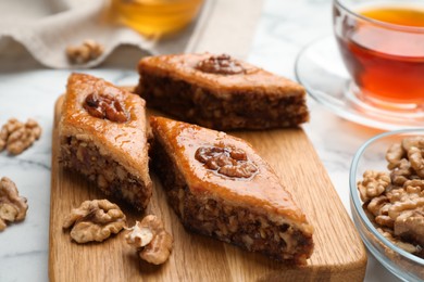 Delicious honey baklava with walnuts served on white marble table, closeup