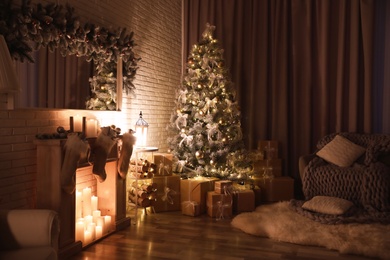 Stylish interior with beautiful Christmas tree and artificial fireplace at night