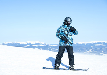 Photo of Male snowboarder on snowy slope in mountains. Winter vacation