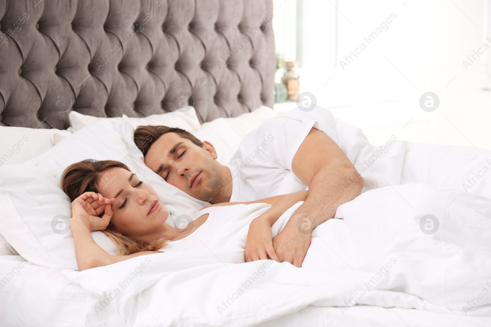 Photo of Young couple sleeping on soft pillows in bed at home