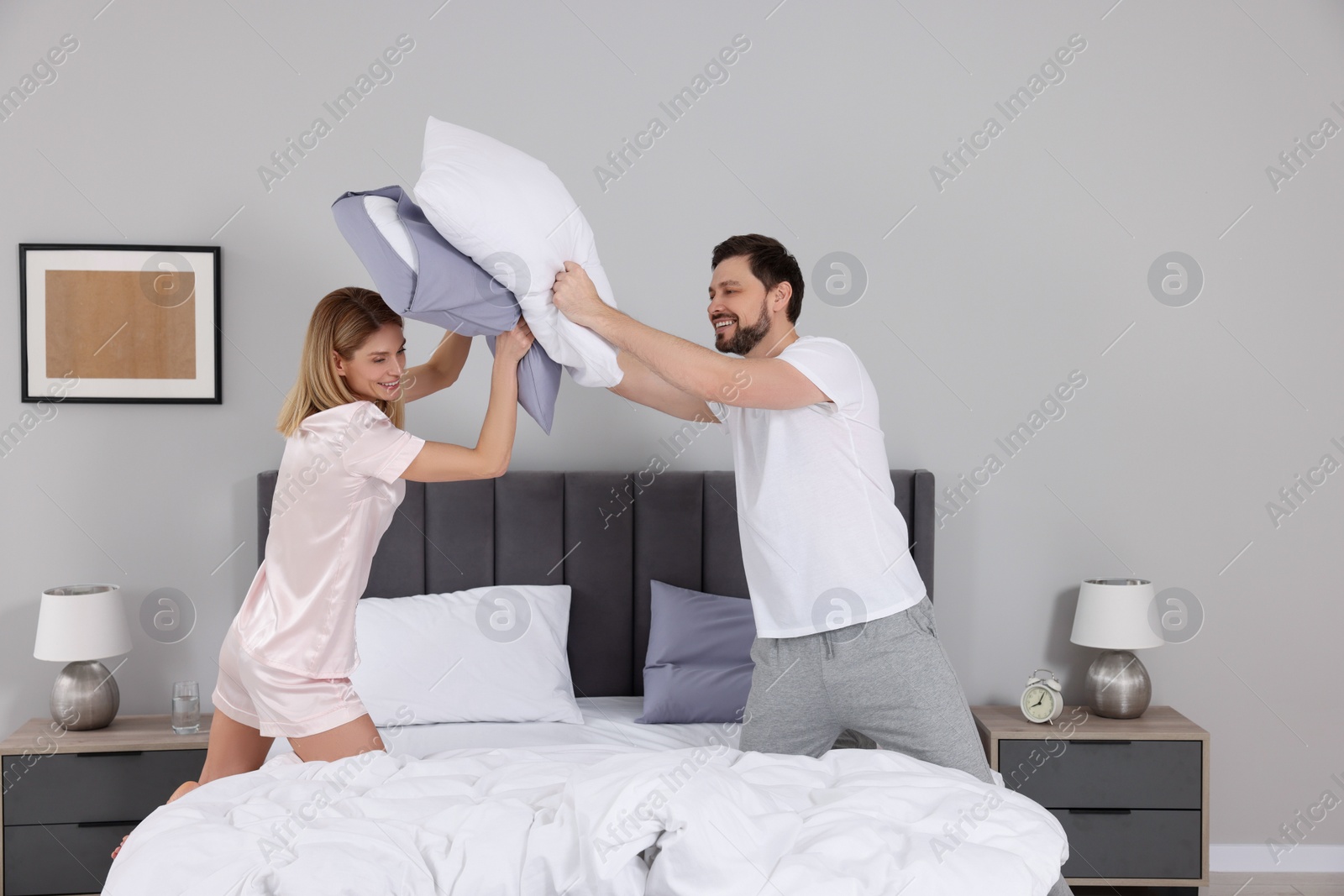 Photo of Couple having pillow fight while changing bed linens at home