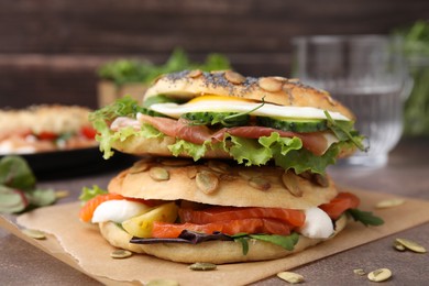 Photo of Stacked tasty bagel sandwiches on brown table, closeup