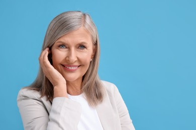 Photo of Portrait of beautiful middle aged woman on light blue background, space for text