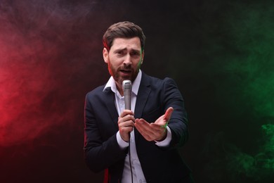 Photo of Emotional man with microphone singing in color lights