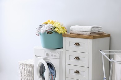 Plastic basket with dirty laundry on washing machine indoors