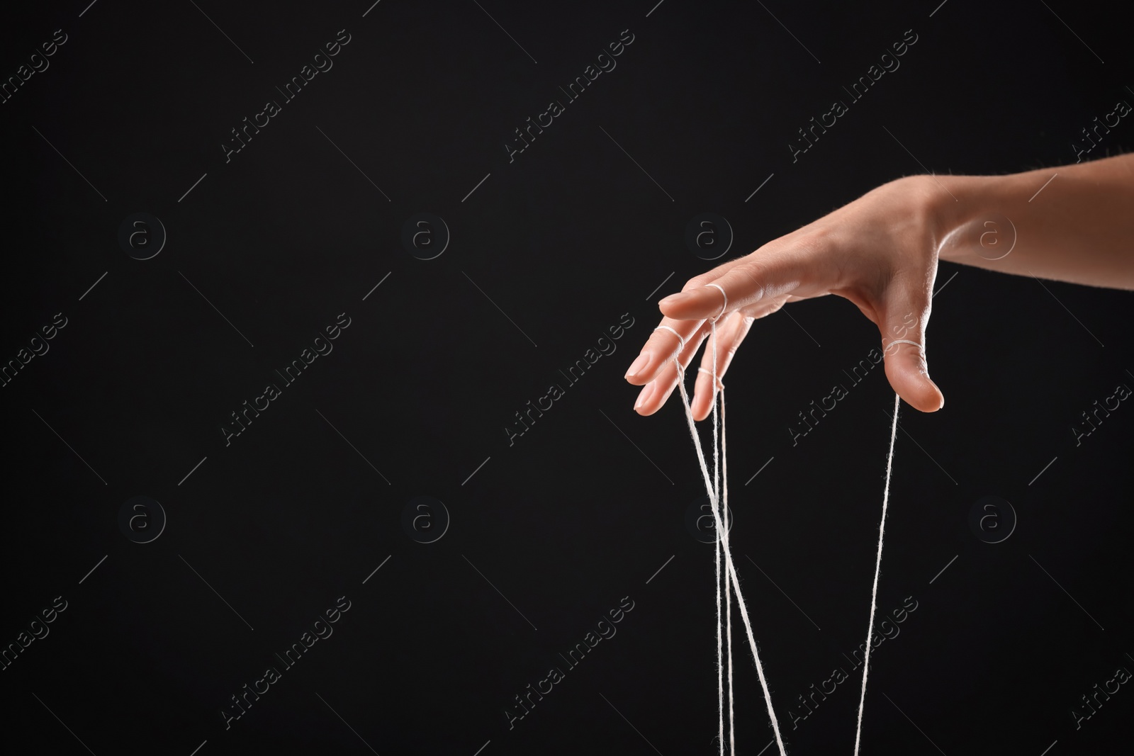 Photo of Woman pulling strings of puppet on black background, closeup. Space for text
