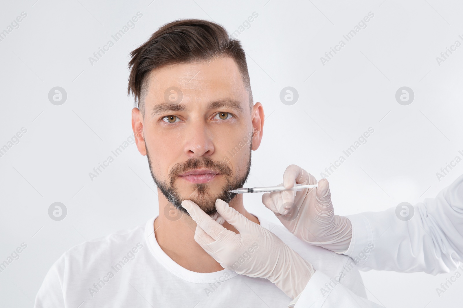 Photo of Mature man getting facial injection on white background. Cosmetic surgery concept