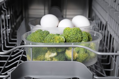 Photo of Cooking raw broccoli and eggs in modern dishwasher, closeup