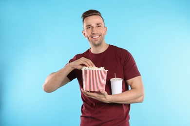 Photo of Man with popcorn and beverage during cinema show on color background