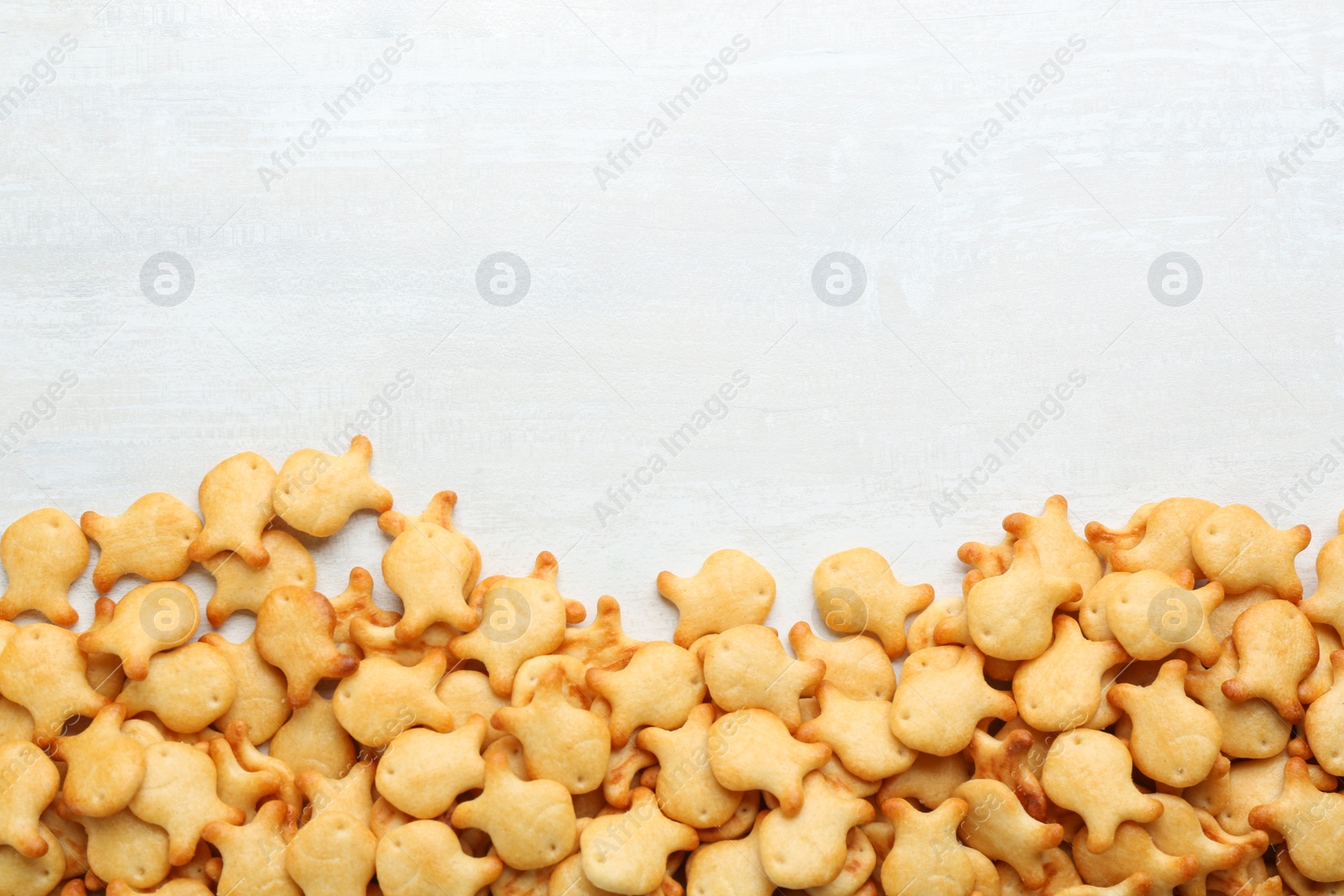 Photo of Delicious goldfish crackers on white table, flat lay. Space for text
