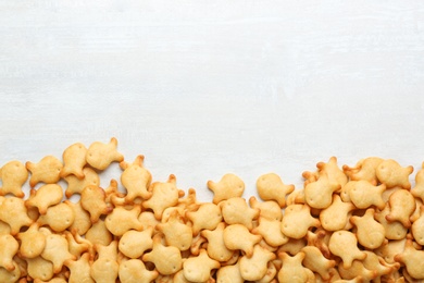 Delicious goldfish crackers on white table, flat lay. Space for text