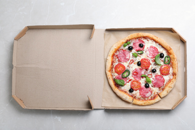 Delicious pizza Diablo in cardboard box on light marble background, top view