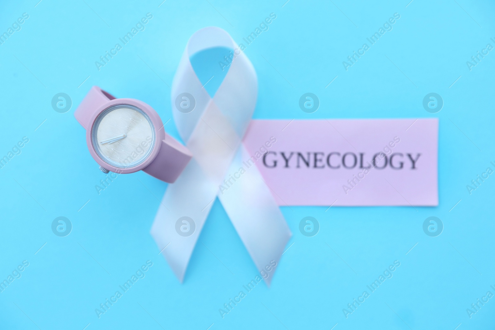 Photo of Flat lay composition with symbolic ribbon of breast cancer awareness and wristwatch on color background. Gynecological care