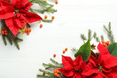 Photo of Flat lay composition with poinsettias (traditional Christmas flowers) and fir branches on white wooden table. Space for text