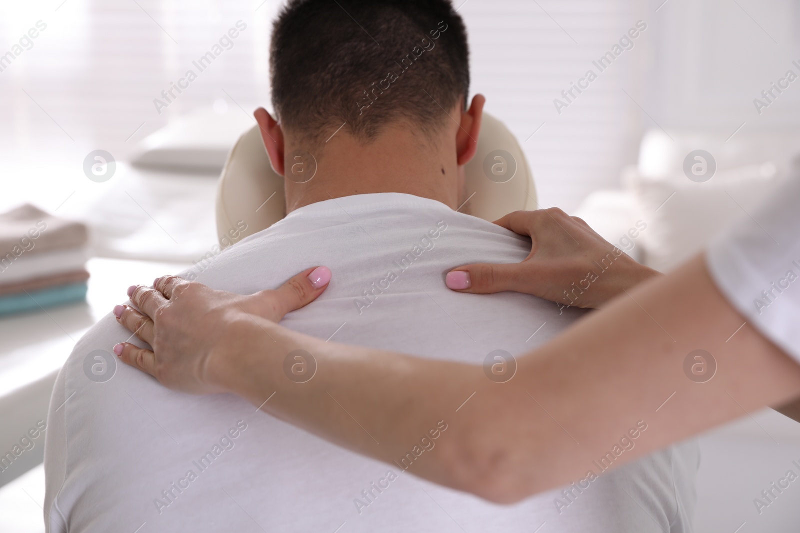 Photo of Man receiving massage in modern chair indoors, closeup