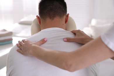 Man receiving massage in modern chair indoors, closeup