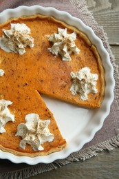 Delicious pumpkin pie with whipped cream on wooden table, top view