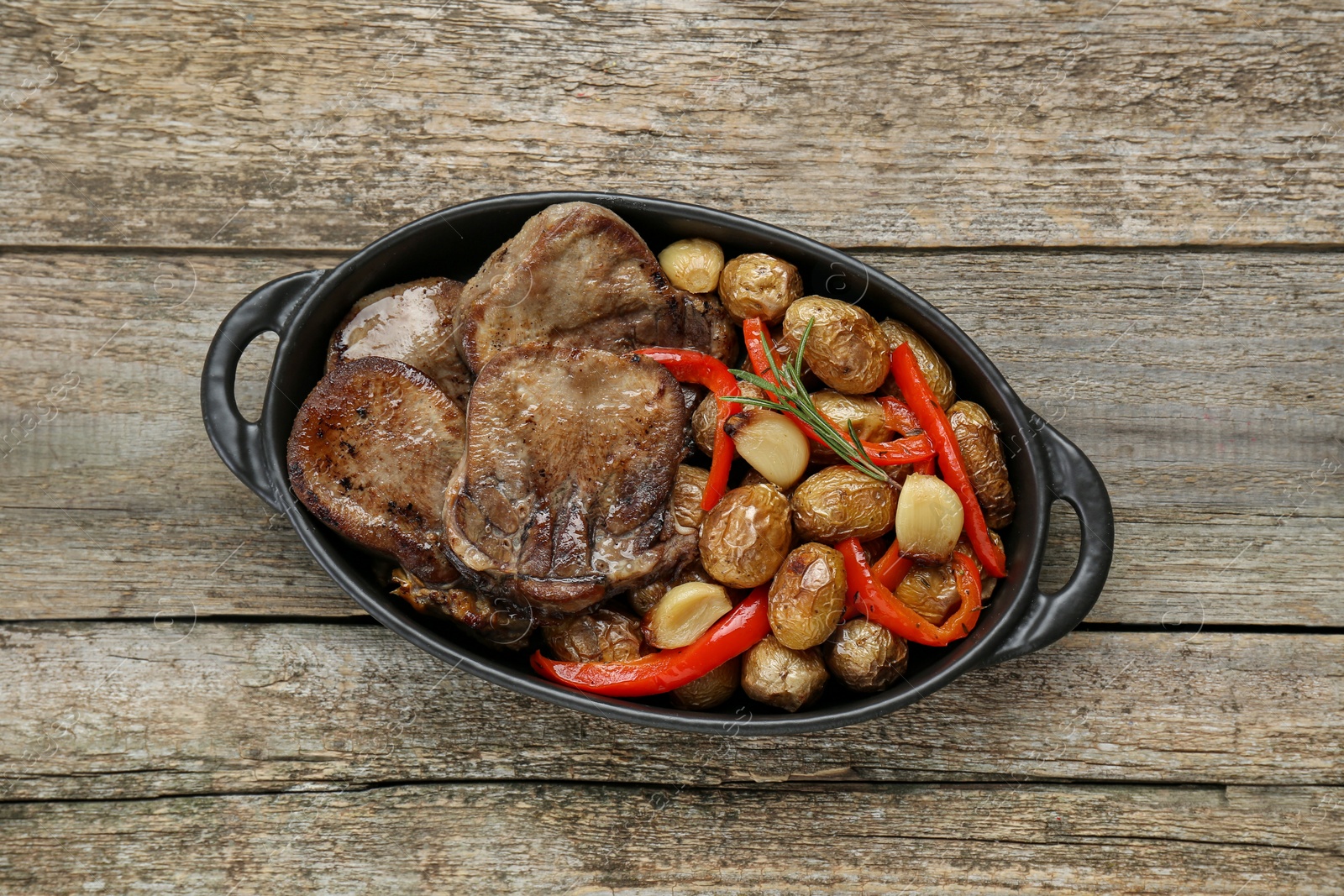 Photo of Tasty beef tongue pieces with potatoes, pepper and rosemary on wooden table, top view