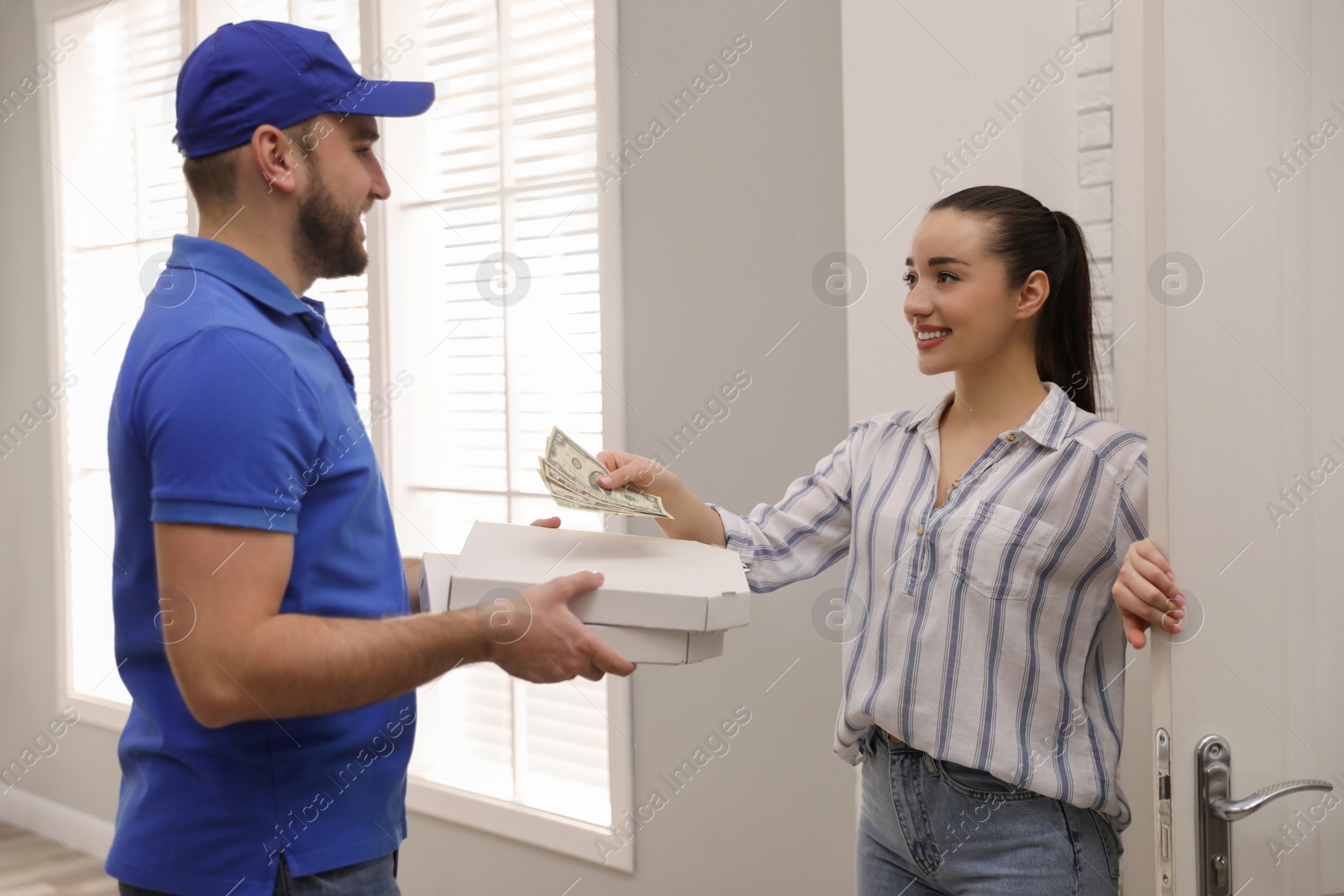 Photo of Young woman giving tips to deliveryman indoors