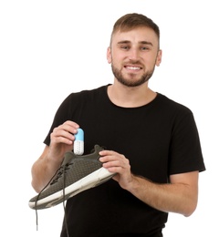 Photo of Young man putting capsule shoe freshener in footwear on white background