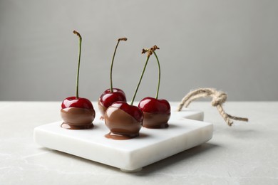 Photo of Sweet chocolate dipped cherries on white table