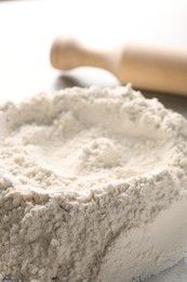 Photo of Pile of flour and rolling pin on grey marble table, closeup