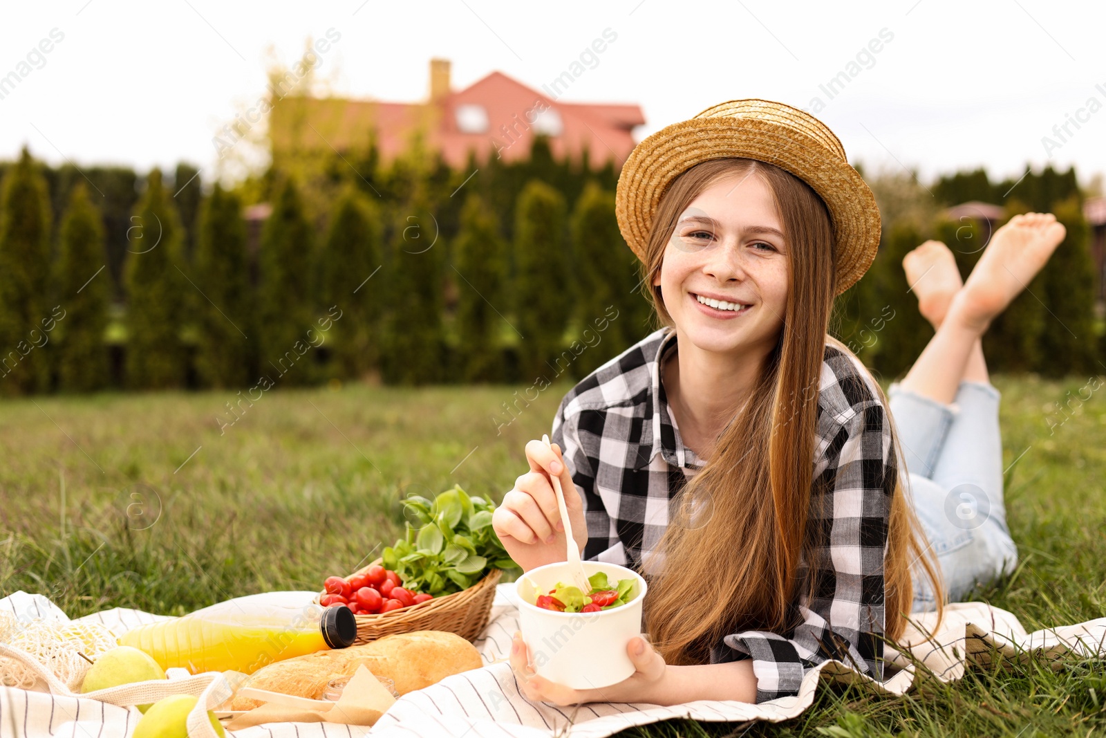 Photo of Happy girl having picnic on green grass in park