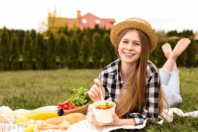 Happy girl having picnic on green grass in park