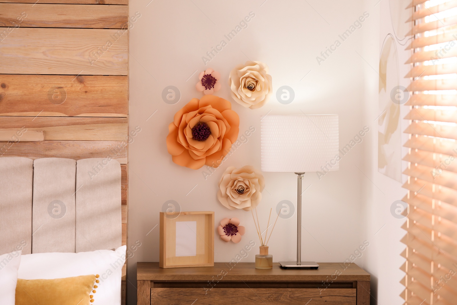 Photo of Stylish bedroom interior with floral decor and wooden bedside table