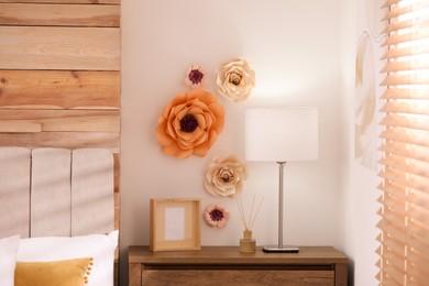 Stylish bedroom interior with floral decor and wooden bedside table