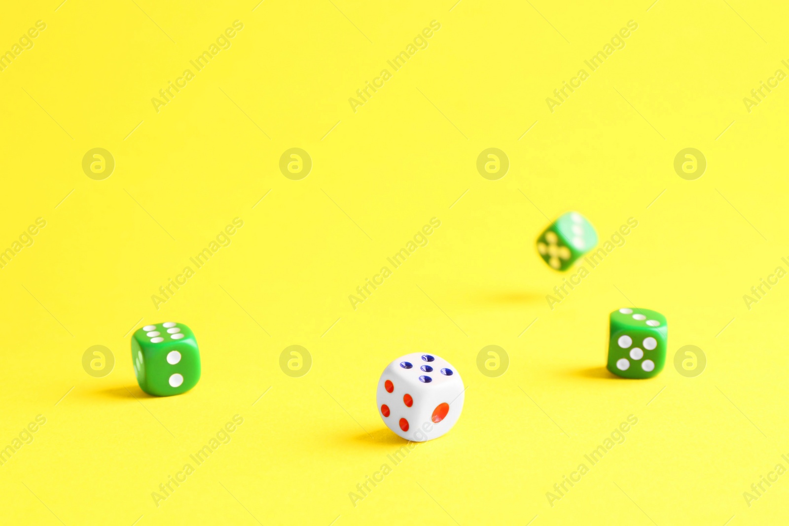 Photo of Many color game dices falling on yellow background