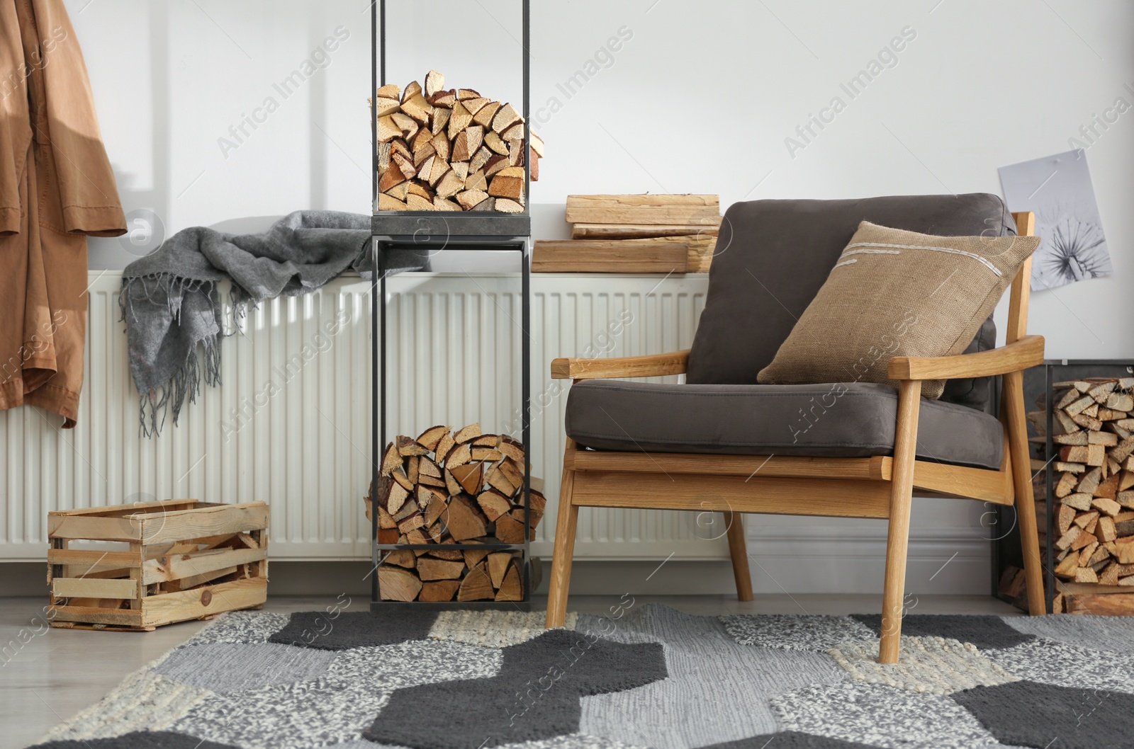 Photo of Firewood near armchair in stylish room interior