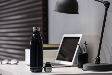 Modern black thermos bottle on table in office