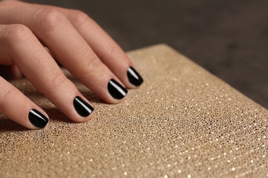 Woman with black manicure holding clutch, closeup. Nail polish trends