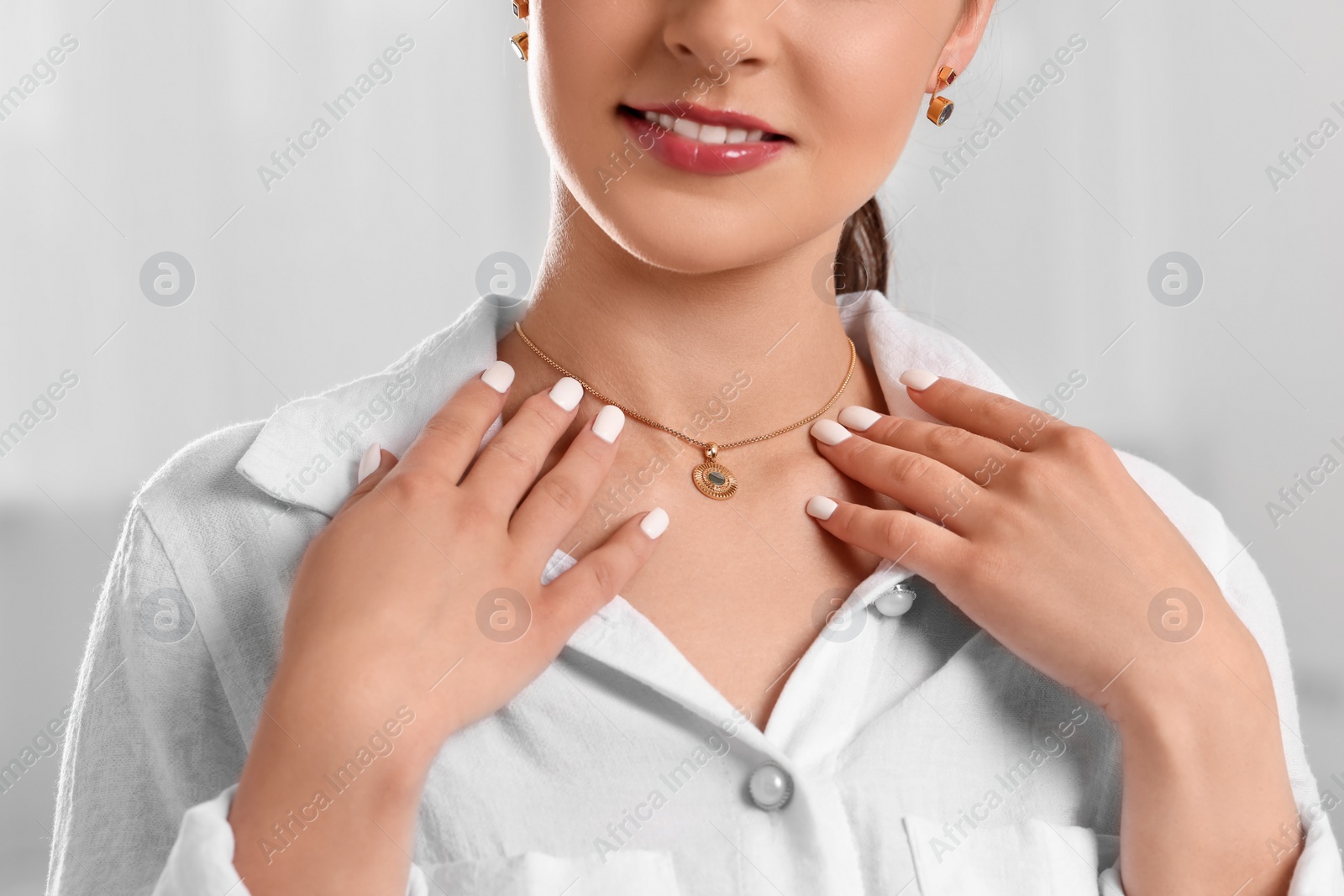 Photo of Beautiful woman with elegant jewelry on light background, closeup