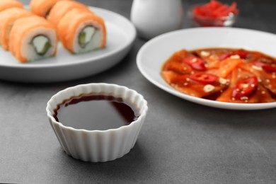 Photo of Tasty sashimi, sushi and soy sauce on grey table